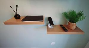 a wooden shelf with a laptop and a plant on a wall at Le Colombier in Wailly