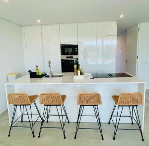 a kitchen with a white counter and three stools at Lux Hiato's Villa in Luz de Tavira +14 photos