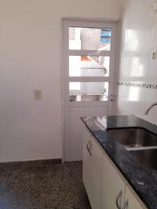 a white kitchen with a sink and a window at Depto Centrico en Planta Alta in Bahía Blanca