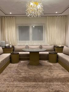a living room with a table and couches and a chandelier at Nara luxe 3 Berkane in Berkawe