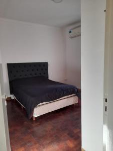 a bedroom with a large bed with a black bedspread at Depto Centrico en Planta Alta in Bahía Blanca +8 photos
