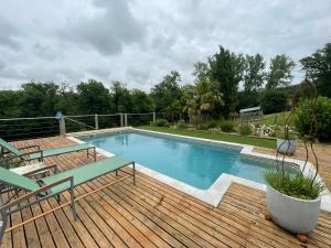 a swimming pool on a wooden deck with two chairs at Les Tables de La Rousse in La Fouillade