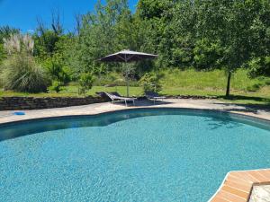 a swimming pool with an umbrella and two chairs and a table at La Mela Rosa Bed & Breakfast in Amandola