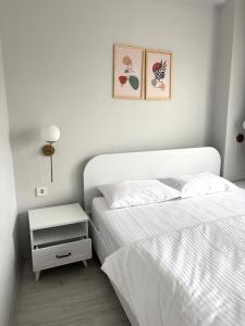 a white bedroom with a bed and a night stand at Sevez Apartments & Homes in Gelibolu +85 photos