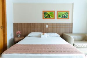 巴西利亚SM1116 Apart Hotel em andar alto região central的卧室配有一张白色床,墙上挂有两张照片