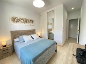 ein Schlafzimmer mit einem Bett mit einer blauen Bettdecke in der Unterkunft Apartamento La Laguna in Chipiona + 36 Fotos
