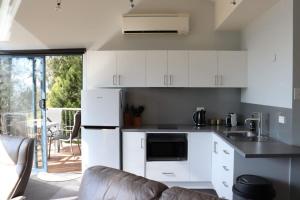a kitchen with white cabinets and a couch at The Tamar Ridge Lookout 2BR 2Bath Suite in Grindelwald