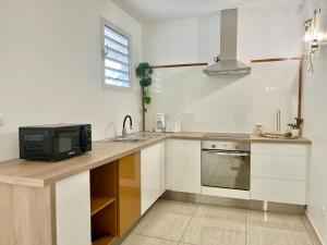 a kitchen with a sink and a microwave at Appartement Cosy La Vanille 1 in Ducos