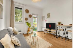 a living room with a gray couch and a tv at Le Capitole - Hyper Centre - Cosy - WIFI in Toulouse