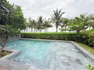 a swimming pool in a yard with palm trees at Villa 3BR Beach Front in Cam Lâm