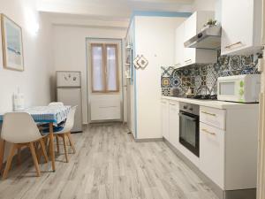 una cucina con elettrodomestici bianchi, tavolo e sedie di Alghero Escape ad Alghero Altre 12 foto