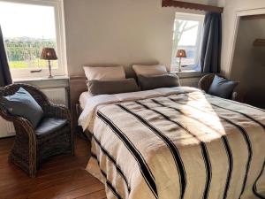 a bedroom with a bed and a chair and a window at Hoeve Molenschot in Molenschot