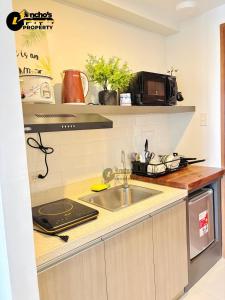une cuisine avec un évier et un micro-ondes dans l'établissement Good Life Luxury Condo, à Sampong