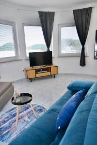 a living room with a blue couch and a tv at Villa Ante Apartments in Blace