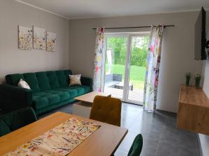 a living room with a green couch and a table at Apartamenty LilaRóż in Brzozie Polskie