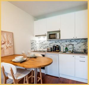 a kitchen with a wooden table and white cabinets at Le Cyclade I Studio I Saint-Julien in Saint-Julien-en-Genevois