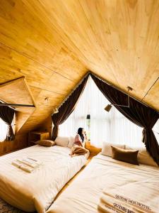una donna seduta su un letto in una stanza di Khách sạn Quỳnh Hoa Tam Đảo a Tam Ðảo