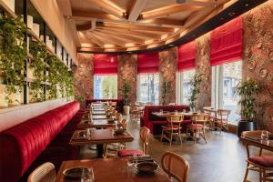 a restaurant with tables and chairs and red booths at Hart Shoreditch Hotel London, Curio Collection by Hilton in London