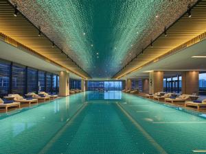 a swimming pool with chairs in a building at Hilton Jiashan in Jiaxing