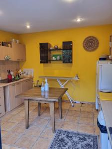 a kitchen with a wooden table and a yellow wall at Vila Florena Garden in Palanga