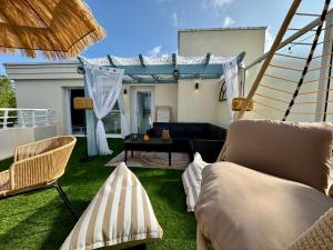 a patio with a couch and a table on the grass at La Baule terrasse, piscine, parking tout confort in La Baule