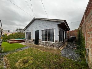 a small house with a black door and a brick building at Tu hogar para vacacionar in Mar del Plata