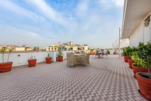 a patio with chairs and tables on a roof at Palm 34 in Jaipur