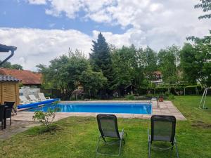 a backyard with a swimming pool and two chairs at Pension Weidengrund in Walsrode