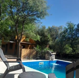 a swimming pool with a chair next to a yard at ENRAMADA Hospedaje en San Marcos Sierras in San Marcos Sierras