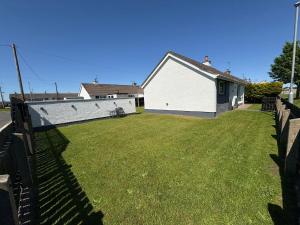 a yard with a fence and a white house at Binevenagh View, Magilligan Limavady Holiday Let in Limavady