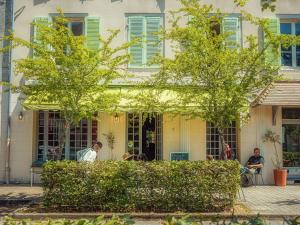two people sitting in front of a building with green shutters at Santat Central hôtel in Bellac