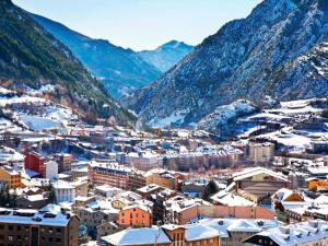a city with snow covered buildings and mountains at Hotel Pere D'Urg 3000 in Encamp