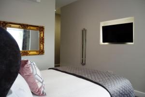 a bedroom with a bed with a mirror and a television at Thomas Paine Hotel in Thetford