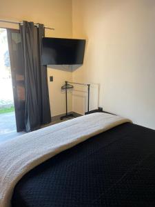 ein Schlafzimmer mit einem Bett mit einem Flachbildfernseher an der Wand in der Unterkunft São Roque Chalés 2 - Pet Friendly in São Roque