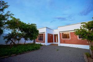 a brick and white building with trees in front of it at Favourites home in Arusha