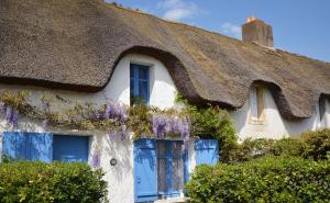 a thatched cottage with purple wisteria on the windows at Maisonnette entre terre et mer in Saint-Malo-de-Guersac