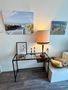 Un escritorio con una lámpara y cuadros en la pared. en Noordwijk Sur-Mer, en Noordwijk aan Zee