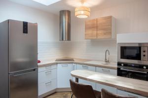 オルレアンにあるLa cour de Jeanneの白いキャビネットとステンレス製の冷蔵庫を備えたキッチン