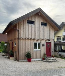 ein großes Holzhaus mit einer roten Tür in der Unterkunft Cozystadl in Vilgertshofen