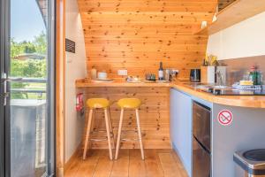 a kitchen with two stools at a counter in a tiny house at Ellerbeck Luxury Pod with Hot Tub at Fell View Park Kirkby Lonsdale in Kirkby Lonsdale +15 photos