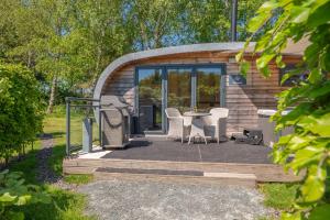 a house with a patio with a grill and chairs at Ellerbeck Luxury Pod with Hot Tub at Fell View Park Kirkby Lonsdale in Kirkby Lonsdale