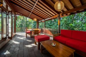 a screened in porch with a red couch and a table at Villa Seremi in Bedahulu
