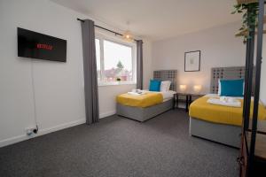 a hotel room with two beds and a window at Beech Palace - Stylish 3Bed Home with Private Garden, Free Parking & Netflix in Coventry