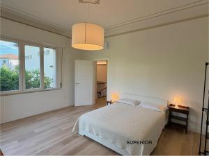 a white bedroom with a bed and two windows at AMALIA Villa & Apartments in Lucca
