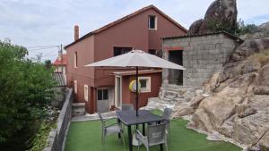 a table with an umbrella in front of a house at Casa Ardora - Playa de Carnota in San Mamede de Carnota