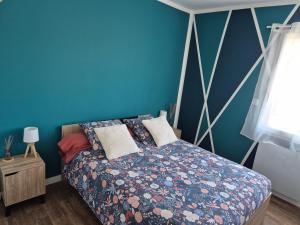 a bedroom with a bed with a blue wall at Charmant logement neuf in Hourtin