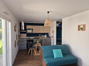a living room with a couch and a kitchen at Charmant logement neuf in Hourtin