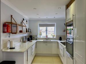 a kitchen with white cabinets and a sink and a window at Heathrow Airport Accommodation in Staines