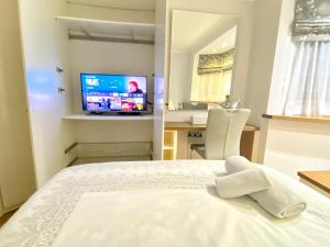 a bedroom with a white bed and a television at Heathrow Airport Accommodation in Staines