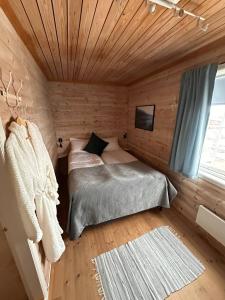 a bedroom with a bed in a wooden room at Havkanten Gjestehus in Husvær